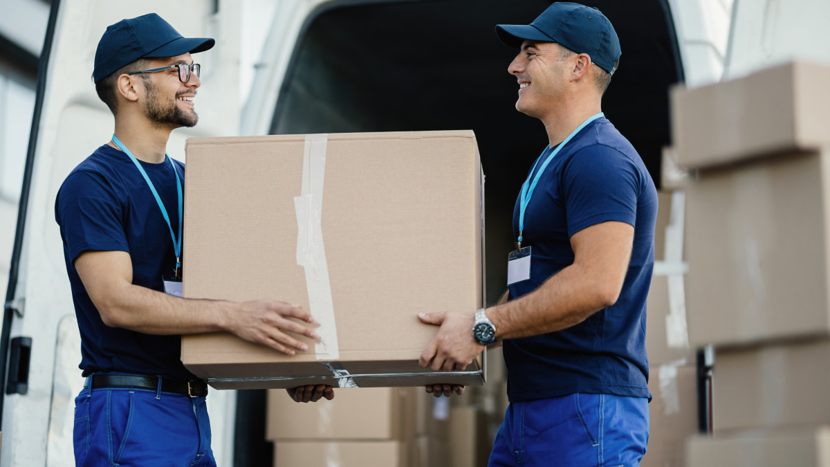 deux déménageurs professionnels s'entraident pour porter un carton