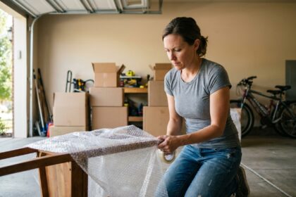 Femme emballant une chaise en bois avec du film à bulles pour la protéger avant un stockage en box