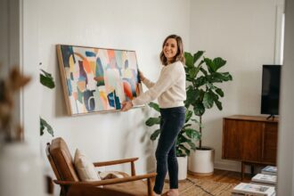 Femme souriante accrochant une toile dans un salon moderne