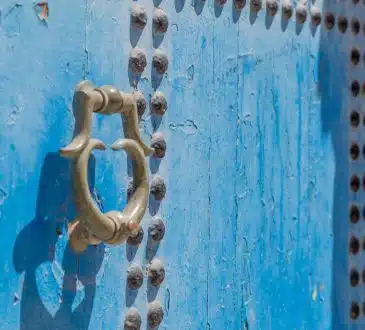 grey door knocker on blue wooden door with rivets