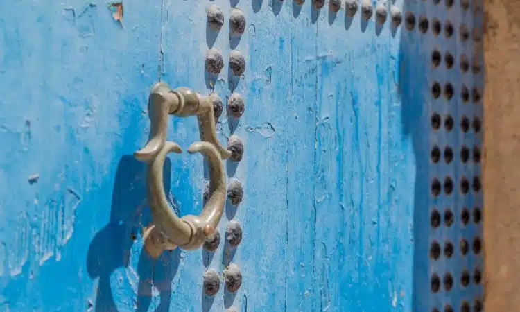 grey door knocker on blue wooden door with rivets